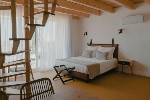 a bedroom with a bed with white sheets and a staircase at Casinhas de Santo António in Alter do Chão