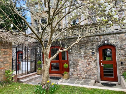 a brick building with red doors and a tree at Ferndale Mews in Bristol