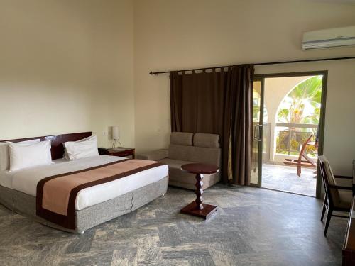 a bedroom with a bed and a chair and a sliding glass door at Veronica Guest House in Lomé