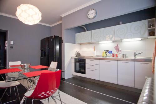 une cuisine avec des chaises rouges, une table et une horloge dans l'établissement Angel Apartment, à Belgrade