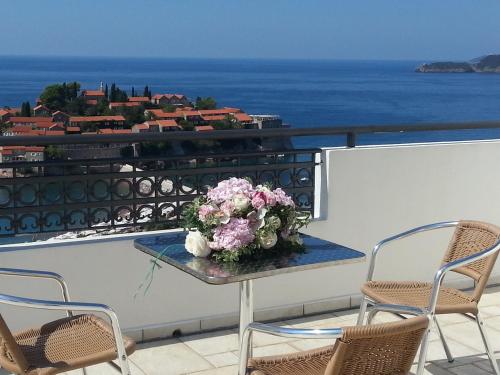 a table with a bouquet of flowers on a balcony at Vila Horizont in Sveti Stefan
