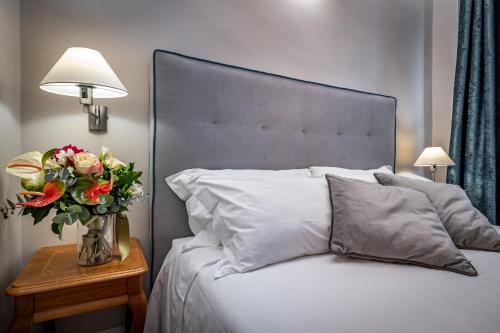 a bed with a vase of flowers on a night stand at Boutique Hotel Borgo in Florence
