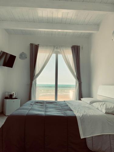 a bedroom with a bed and a window with the beach at CARFAGNINI ROOMS in Termoli