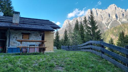 a cabin with a fence and mountains in the background at Baita Dani in San Martino di Castrozza