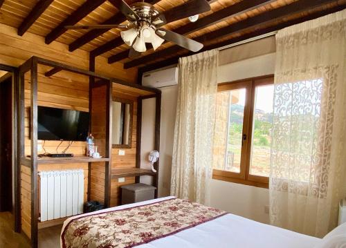 a bedroom with a bed with a ceiling fan and a window at Nassamat Boutique Hotel in Al Bārūk