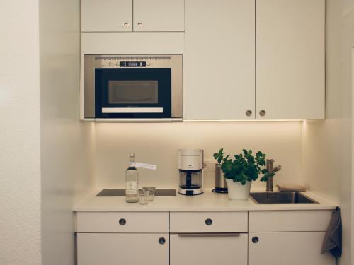 a kitchen counter with a coffee maker and a microwave at Eremitage Sylt in Wenningstedt