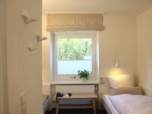 a bedroom with a window and a bed and a table at Eremitage Sylt in Wenningstedt