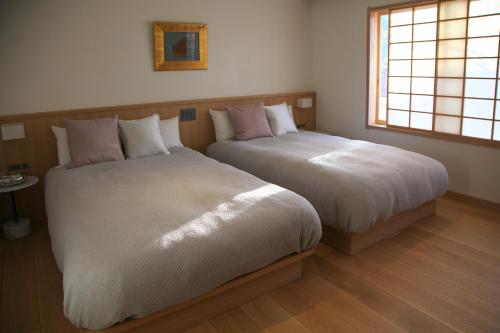 two beds sitting next to each other in a bedroom at Arima Onsen Takayamaso Hanano in Kobe