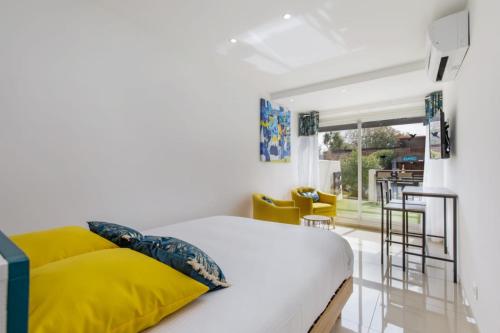 une chambre avec un lit blanc avec des oreillers jaunes dans l'établissement La Belle Vie - village naturiste PN4, au Cap d'Agde