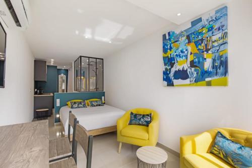 une chambre avec un lit et deux chaises jaunes dans l'établissement La Belle Vie - village naturiste PN4, au Cap d'Agde