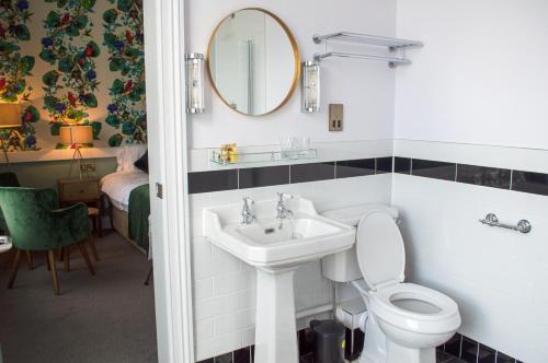 a bathroom with a sink and a toilet and a mirror at The Clock Face Prescot in Prescot
