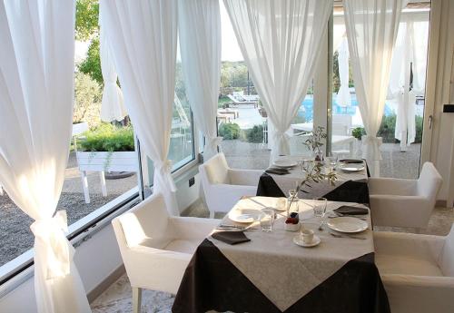 een restaurant met witte tafels en witte stoelen en ramen bij Relais Lali' in Mottola