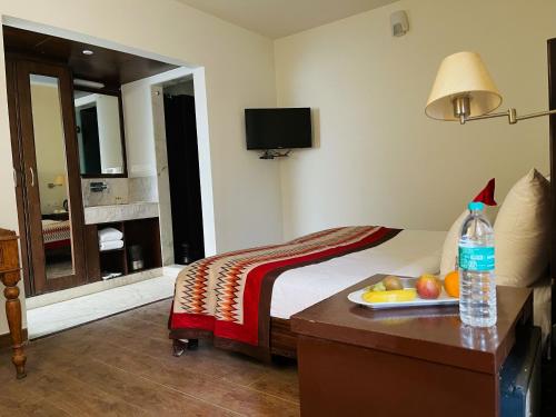 a hotel room with a bed with a tray of fruit on a table at The Orion Express in Jaipur