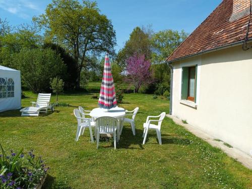 een tafel en stoelen met een parasol op een tuin bij Le domaine du bengal 2 in Veuil