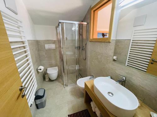 uma casa de banho com um lavatório, um chuveiro e um WC. em Hotel Elisabeth Panorama em Antermoia