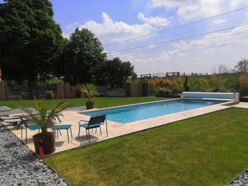 a swimming pool in a yard with chairs and a table at Cottage l'Orée du Cher in Chissay-en-Touraine