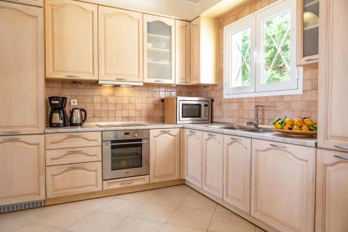 a kitchen with white cabinets and a sink and a microwave at Epidavros Land villa Elia in Ancient Epidavros