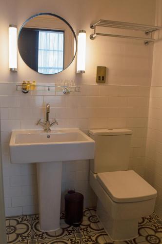 Un baño con lavabo, inodoro y espejo. en The Clock Face Prescot, en Prescot