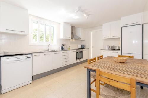 a kitchen with white cabinets and a wooden table at Biniancolla Ginesta in Biniancolla