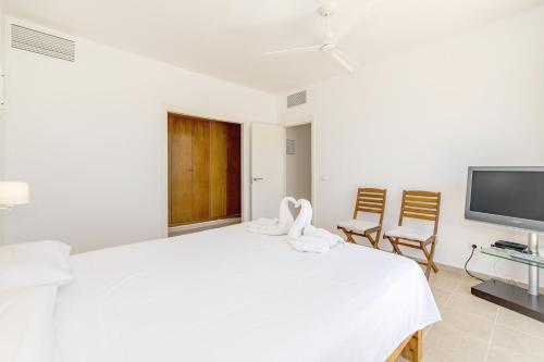 a white bedroom with a large bed and a tv at Biniancolla Ginesta in Biniancolla