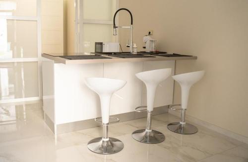 a kitchen with two white bar stools and a counter at THE HOUSE OF EVELYN in Catania
