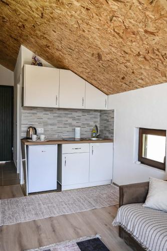 a kitchen with white cabinets and a couch in a room at Elem apartmani Skver in Tuzla