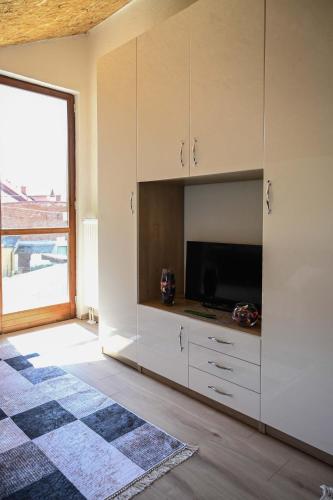 a kitchen with white cabinets and a flat screen tv at Elem apartmani Skver in Tuzla