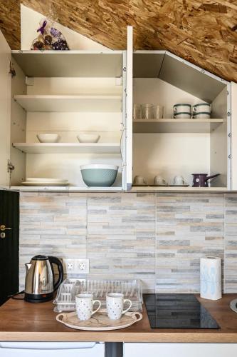 a kitchen with white cabinets and a table with cups at Elem apartmani Skver in Tuzla