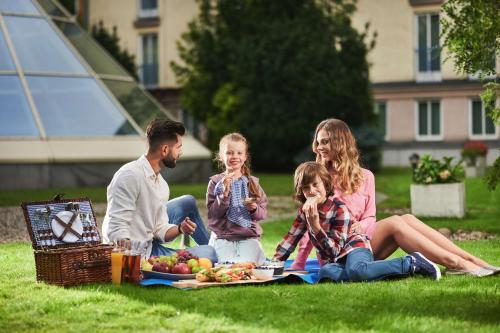 a family sitting on the grass with a picnic at Radisson Blu Sobieski in Warsaw