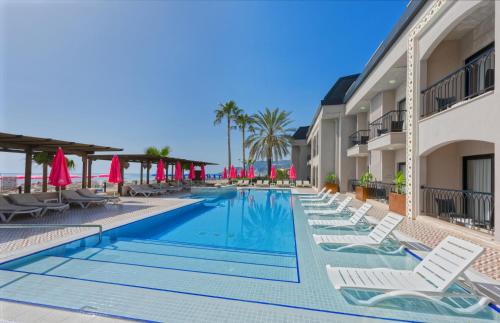 a swimming pool at a resort with chairs and umbrellas at Alaaddin Beach Hotel - Adult Only in Alanya