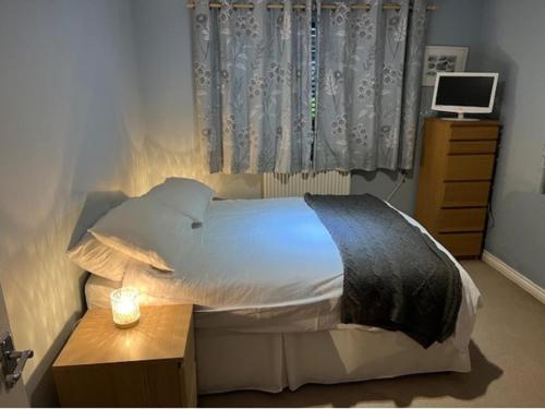 ein Schlafzimmer mit einem Bett und einem Tisch mit einer Lampe in der Unterkunft Captivating Apartment in Copthorne near Gatwick in Copthorne