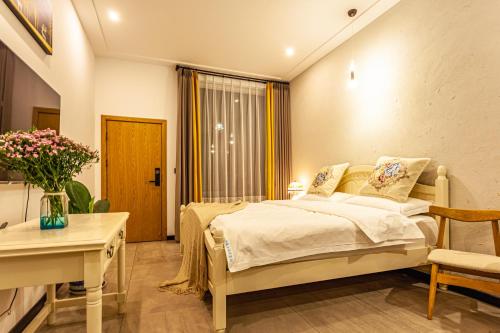 a bedroom with a bed and a table and a desk at Blue Sea Hotel in Dali