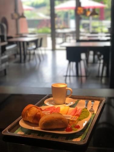 a tray with a plate of food and a cup of coffee at Serways Hotel Spessart in Rohrbrunn