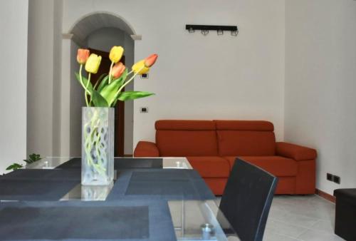 a vase of flowers on a glass table with a couch at Civico 22 in Trapani