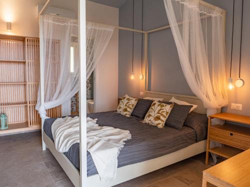 a bedroom with a canopy bed with curtains at B&B Sole Mare Luna in Lu Lioni