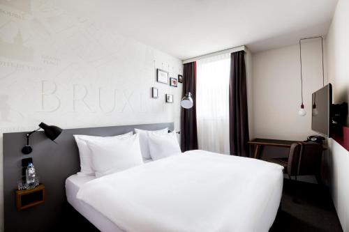 Habitación de hotel con cama blanca y almohadas blancas en Pentahotel Brussels Airport en Diegem