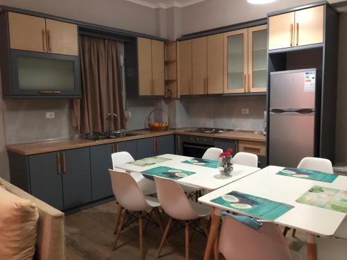 a kitchen with a table with chairs and a refrigerator at Genci Seaview Apartaments@AlbaResidence in Sarandë