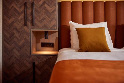 a bed with an orange headboard and a yellow pillow at Van der Valk Hotel Dennenhof in Brasschaat