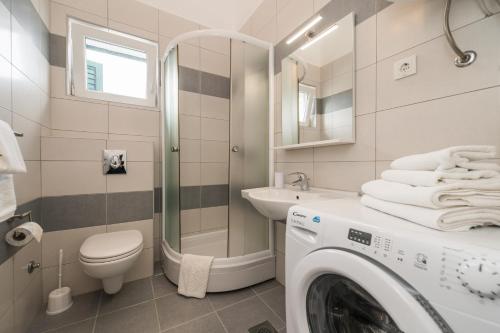 a bathroom with a washing machine and a sink at Apartmani Bella Luce in Pašman