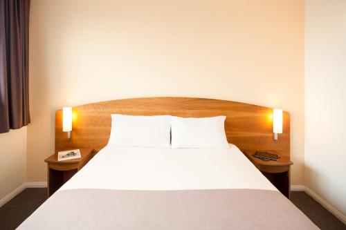 a bedroom with a large bed with two night stands at ibis Hotel Northampton Centre in Northampton