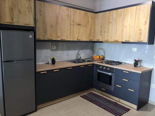 a kitchen with a black refrigerator and wooden cabinets at Genci Seaview Apartaments@AlbaResidence in Sarandë