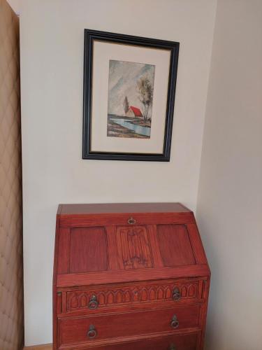 a wooden dresser with a picture on the wall at Retro Cosy Apartment in Mirijevo