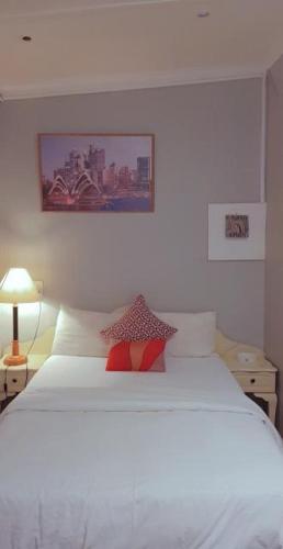a white bed with a red pillow on top of it at Bedfort Accommodation in Cape Town