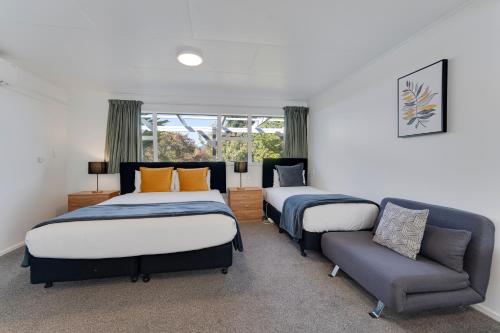 two beds in a room with a couch and a chair at Archway Motels & Chalets in Wanaka
