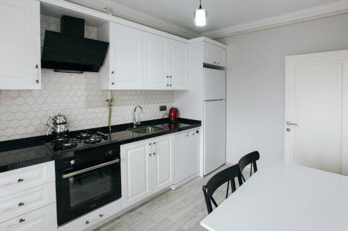 a kitchen with white cabinets and a white table and chairs at Melissa Suite in Trabzon