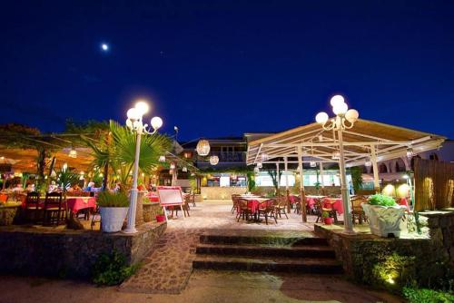 a patio with tables and chairs at night at Molfetta Beach Hotel  in Gouvia