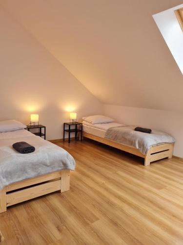 two beds in a room with wooden floors at Apartamenty Pod Dachem in Lutowiska