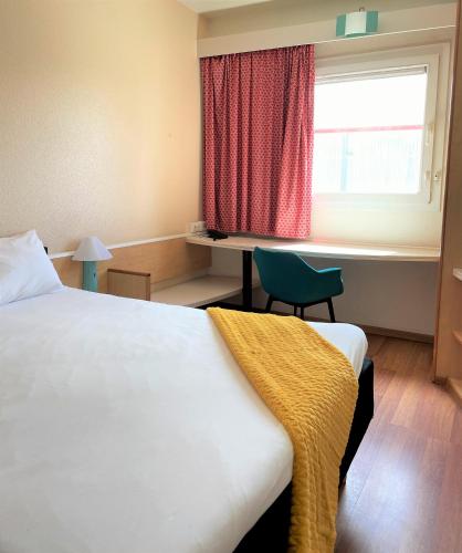 a bedroom with a bed and a desk and a window at Hotel ibis Porto Sul Europarque in Santa Maria da Feira