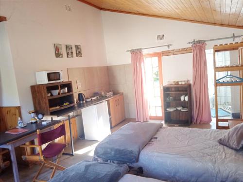a bedroom with a bed and a desk and a kitchen at Rheola's Guest Cottage in Harrismith