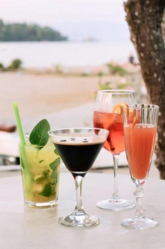 three wine glasses sitting on a table with drinks at Molfetta Beach Hotel  in Gouvia